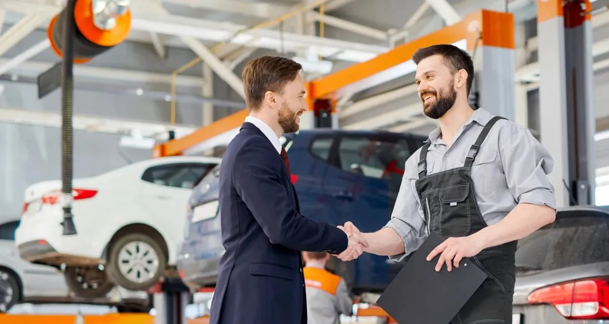 Carrozziere autosicura con cliente Carrozziere di autosicura stringe la mano a un cliente